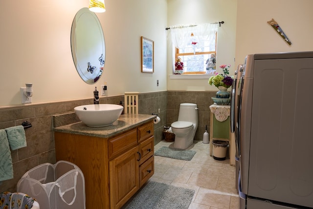 bathroom featuring toilet, washer / dryer, tile walls, and vanity