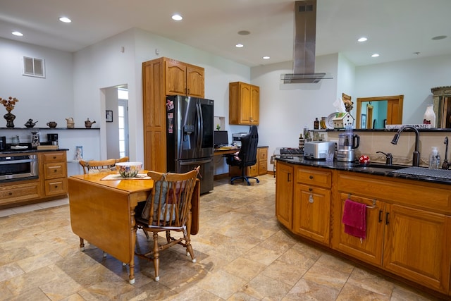 kitchen with sink, stainless steel fridge with ice dispenser, island exhaust hood, and dark stone counters