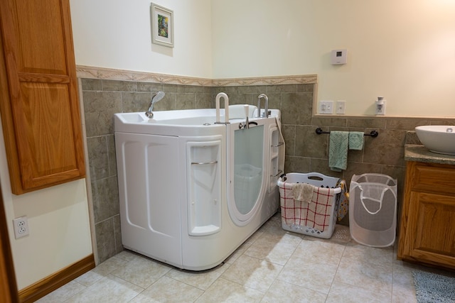 laundry area featuring light tile patterned floors, tile walls, washer / dryer, and sink