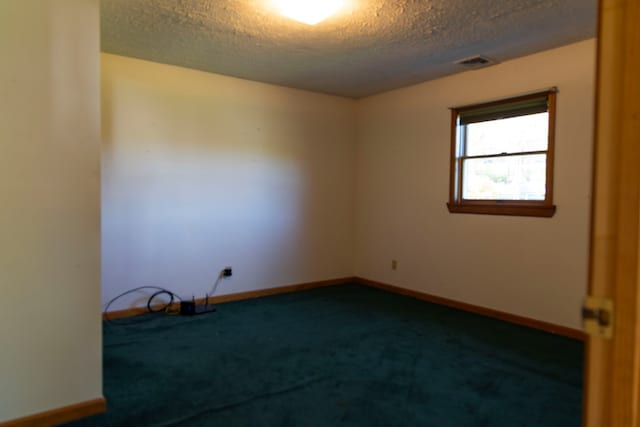 spare room with a textured ceiling and dark carpet