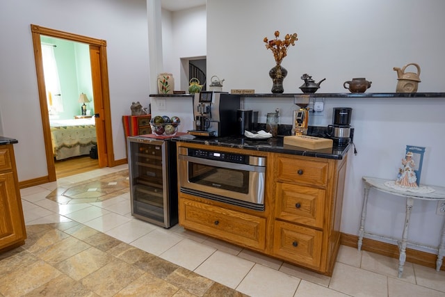 kitchen with light tile patterned floors, wine cooler, and dark stone counters