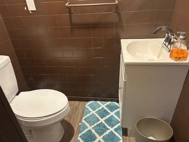 bathroom with hardwood / wood-style floors, vanity, toilet, and tile walls