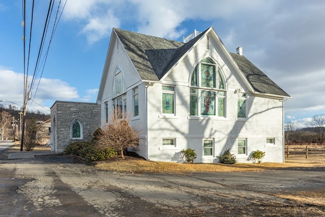 view of property exterior with stucco siding, roof with shingles, and a chimney