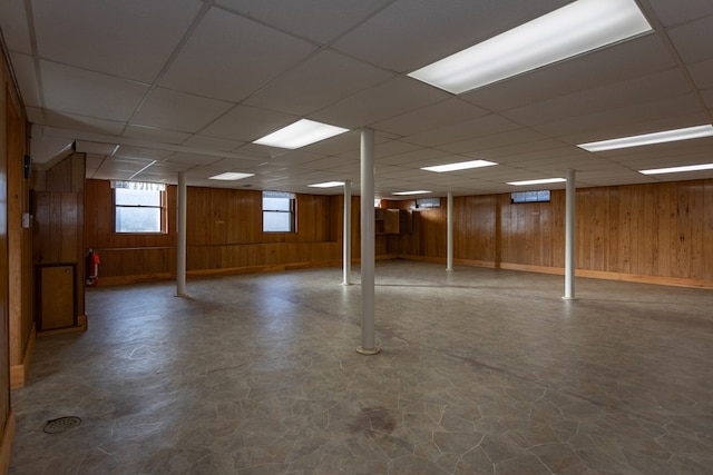 basement featuring a drop ceiling and wooden walls