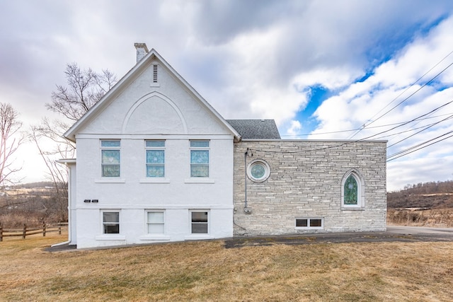 rear view of property featuring a yard and stucco siding