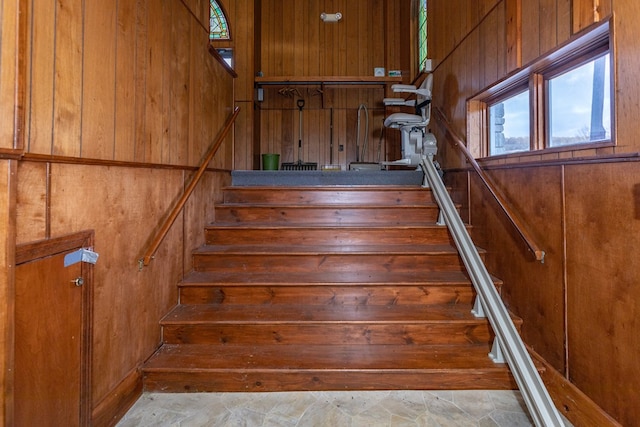 stairs featuring wooden walls and stone finish floor