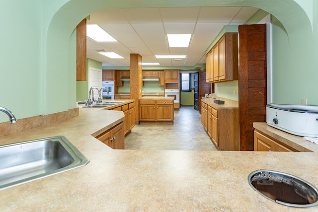 kitchen featuring light countertops, a drop ceiling, and a sink