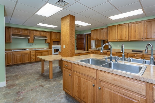 kitchen featuring visible vents, a sink, light countertops, under cabinet range hood, and white oven