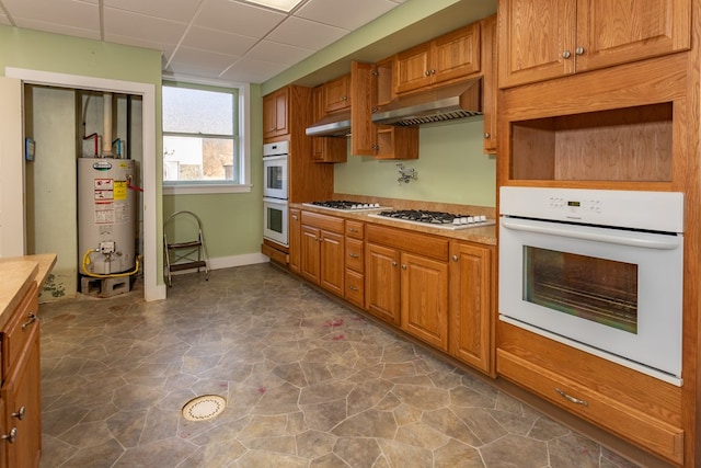 kitchen featuring under cabinet range hood, a drop ceiling, gas water heater, and white appliances