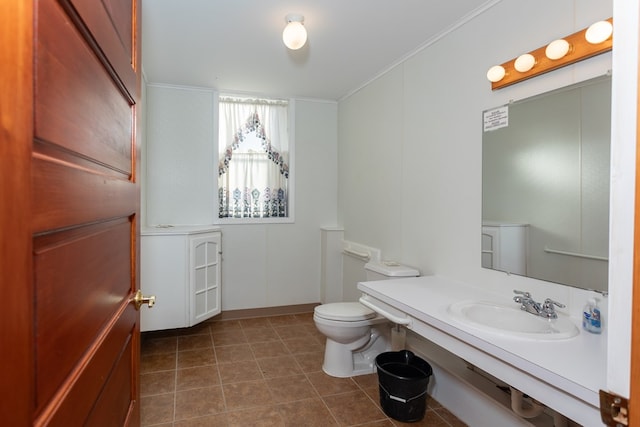 bathroom with tile patterned floors, toilet, crown molding, and a sink