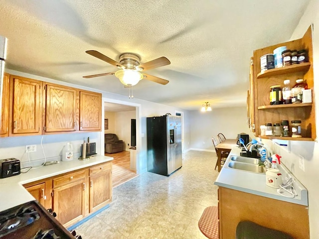 kitchen with stainless steel refrigerator with ice dispenser, ceiling fan, sink, and a textured ceiling