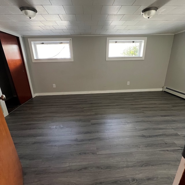 empty room with a baseboard radiator and dark hardwood / wood-style floors