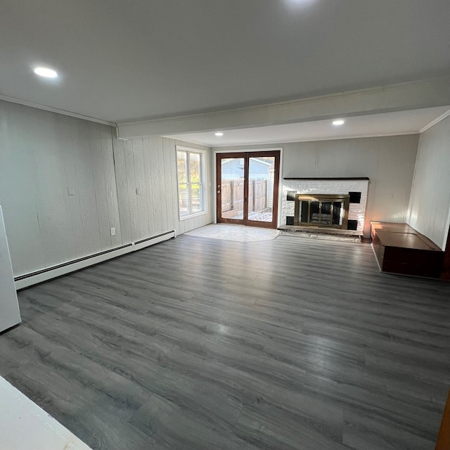 unfurnished living room featuring wood-type flooring, baseboard heating, and crown molding