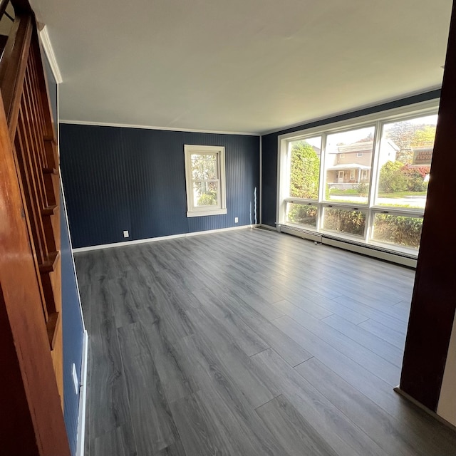 unfurnished room featuring hardwood / wood-style floors, a baseboard heating unit, and ornamental molding