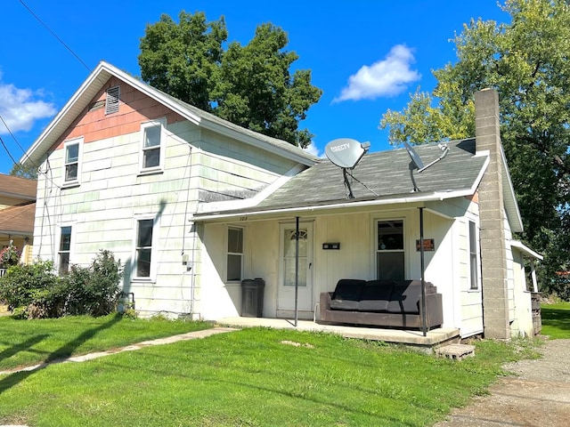 rear view of house with covered porch and a yard