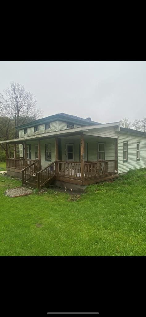 back of property with covered porch and a lawn