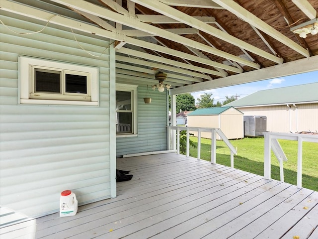 wooden terrace featuring a lawn and a storage shed