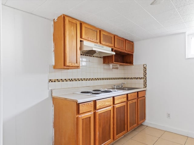 kitchen featuring decorative backsplash, white cooktop, sink, and light tile patterned floors