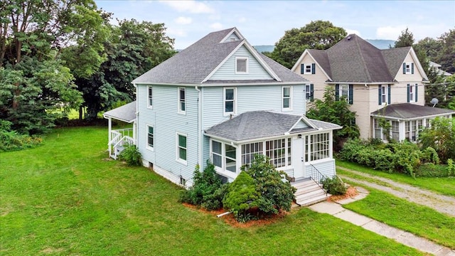 rear view of property featuring a lawn and a sunroom