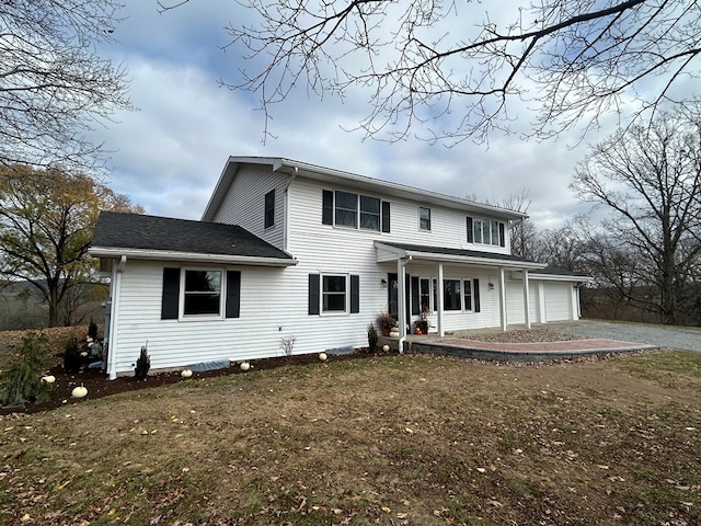 rear view of house featuring covered porch, a garage, and a lawn