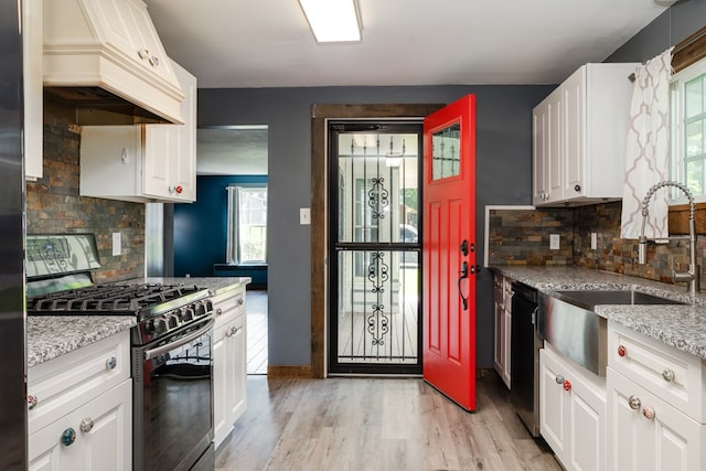 213 Holden St, Osceola, PA 16942 - kitchen with stainless steel range with gas stovetop, custom exhaust hood, a sink, light wood-type flooring, and backsplash