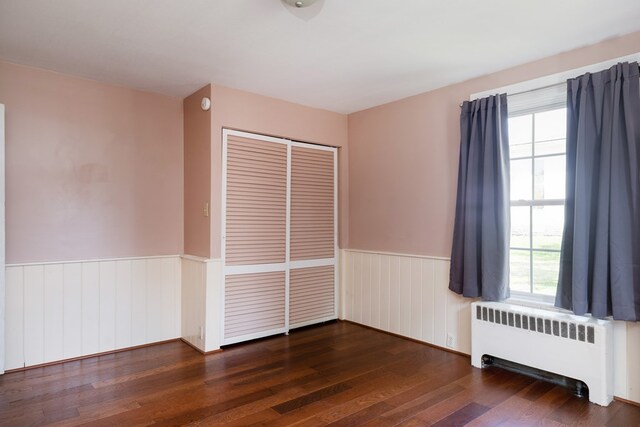 213 Holden St, Osceola, PA 16942 - empty room with radiator heating unit, a wainscoted wall, healthy amount of natural light, and wood finished floors