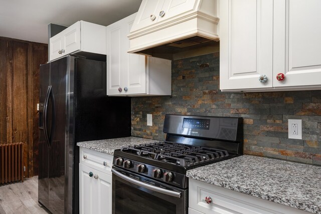 213 Holden St, Osceola, PA 16942 - kitchen featuring stainless steel gas range, radiator heating unit, custom range hood, black refrigerator with ice dispenser, and light stone counters