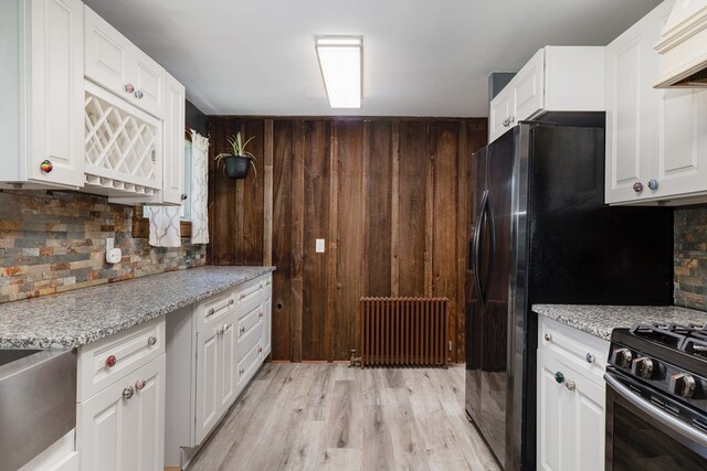 213 Holden St, Osceola, PA 16942 - kitchen with radiator heating unit, tasteful backsplash, white cabinetry, light wood-style flooring, and wooden walls