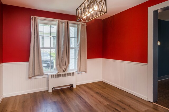 213 Holden St, Osceola, PA 16942 - unfurnished dining area with radiator heating unit, wainscoting, wood finished floors, and a chandelier