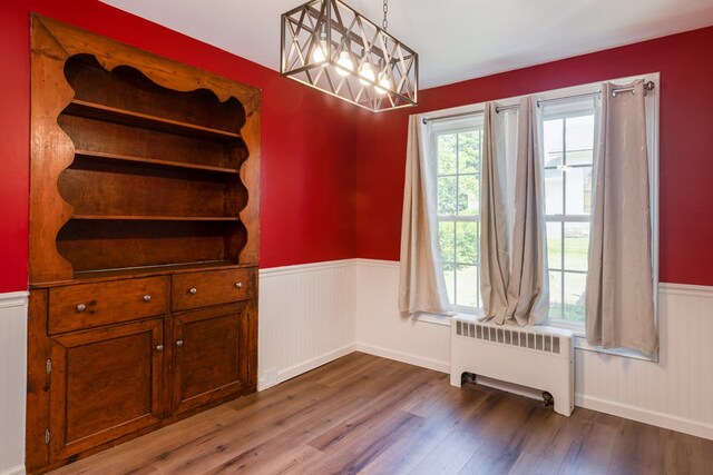 213 Holden St, Osceola, PA 16942 - unfurnished dining area featuring radiator, wainscoting, wood finished floors, and a chandelier