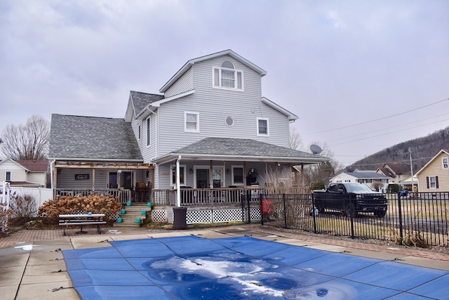 back of property featuring a porch and a covered pool