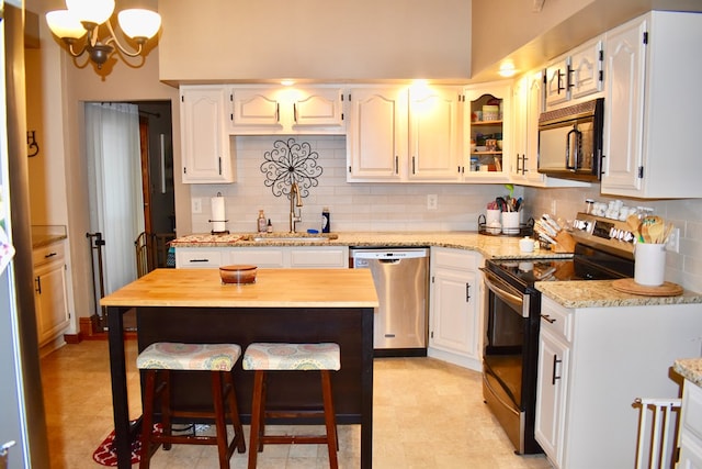 kitchen featuring sink, white cabinetry, backsplash, stainless steel appliances, and light stone countertops