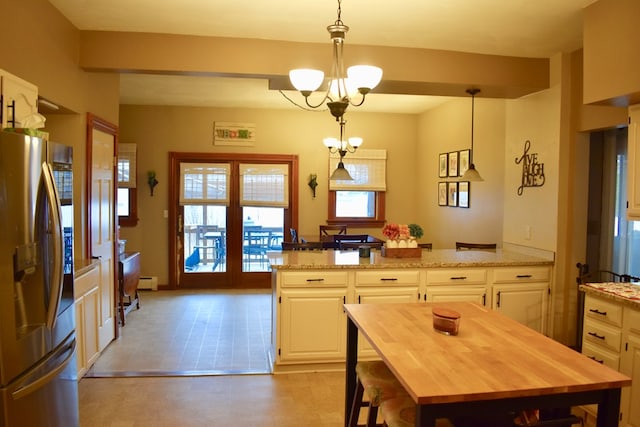 kitchen with a kitchen island, decorative light fixtures, stainless steel fridge, light stone counters, and an inviting chandelier