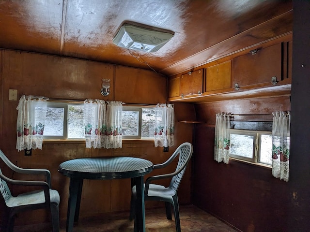 dining space with wood ceiling and wooden walls