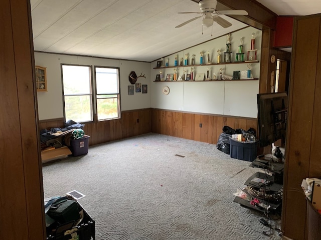 misc room featuring carpet, ceiling fan, wood walls, and vaulted ceiling