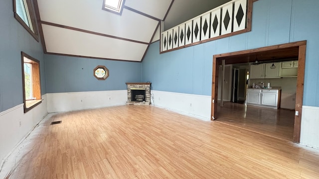 8380 Sheshequin Rd, Athens, PA 18810 - unfurnished living room featuring high vaulted ceiling, wood finished floors, a brick fireplace, beam ceiling, and a wainscoted wall