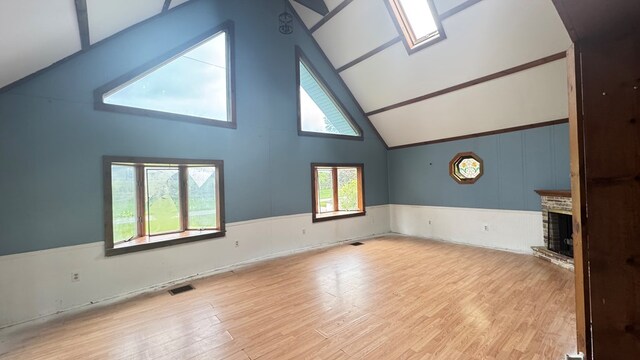 8380 Sheshequin Rd, Athens, PA 18810 - unfurnished living room with high vaulted ceiling, wood finished floors, a brick fireplace, a wainscoted wall, and arched walkways