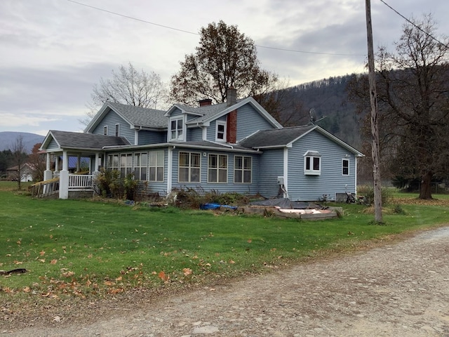 exterior space featuring a sunroom, a front lawn, and a mountain view