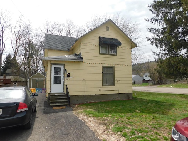 traditional home with roof with shingles, entry steps, and a front lawn