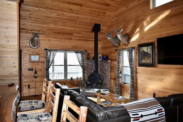 living room featuring lofted ceiling, wood walls, a wood stove, and wooden ceiling