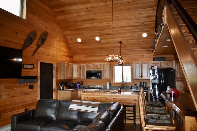 kitchen with pendant lighting, wood walls, high vaulted ceiling, black fridge, and range