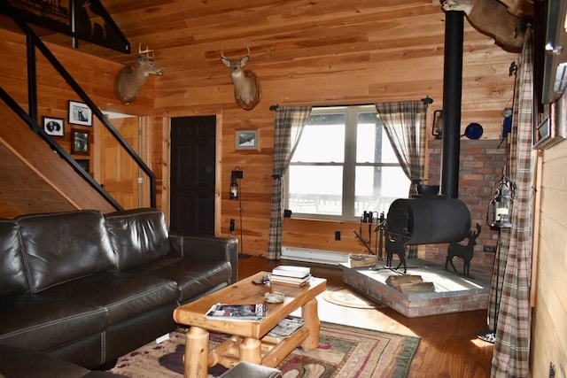 living room with wood-type flooring, a baseboard radiator, a wood stove, and wood walls