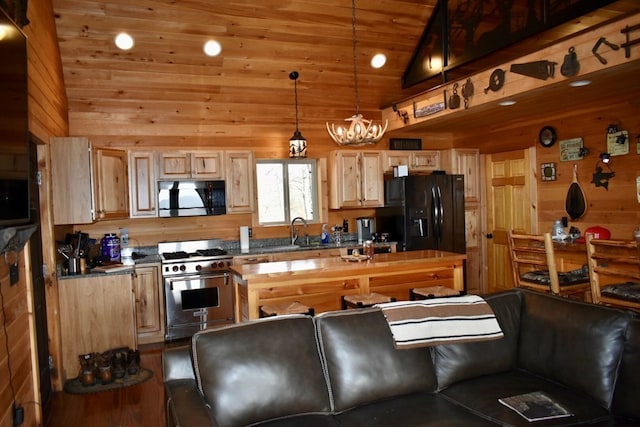 kitchen featuring black appliances, decorative light fixtures, wood walls, and vaulted ceiling