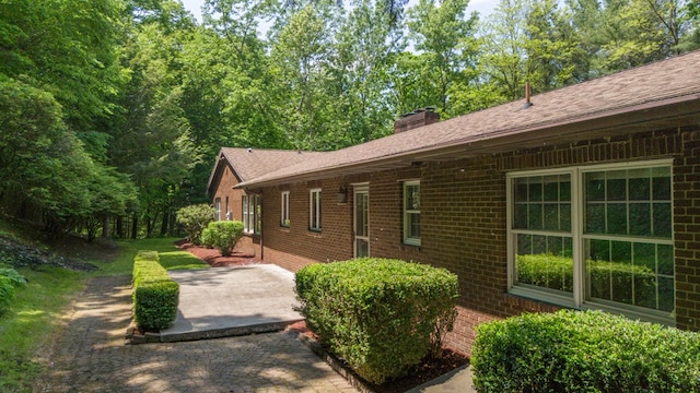105 Laurel Ln, Sayre, PA 18840 - view of side of property with brick siding, a patio area, a chimney, and roof with shingles