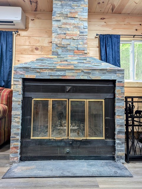 198 Spring Run Rd, Smethport, PA 16749 - detailed view of wood finished floors, a stone fireplace, a wall unit AC, and wooden ceiling