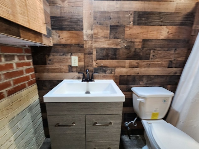 bathroom featuring vanity, wood walls, and toilet