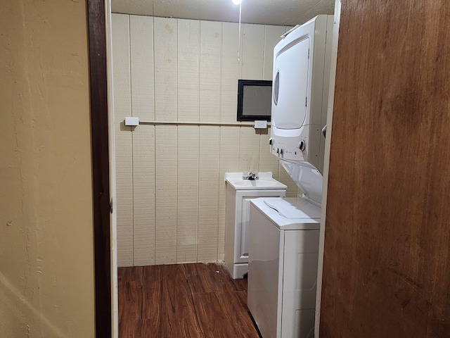 washroom featuring dark hardwood / wood-style floors and stacked washing maching and dryer