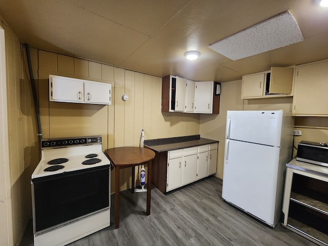 kitchen with wooden walls, white cabinetry, white refrigerator, electric range, and light hardwood / wood-style floors