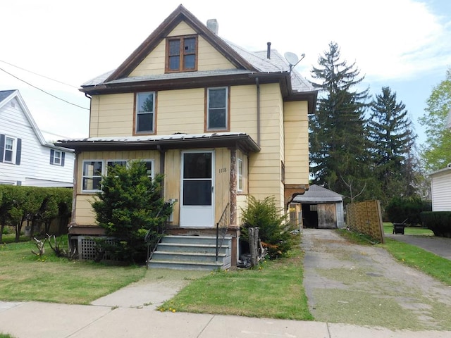 american foursquare style home featuring entry steps, an outdoor structure, a chimney, and a front yard