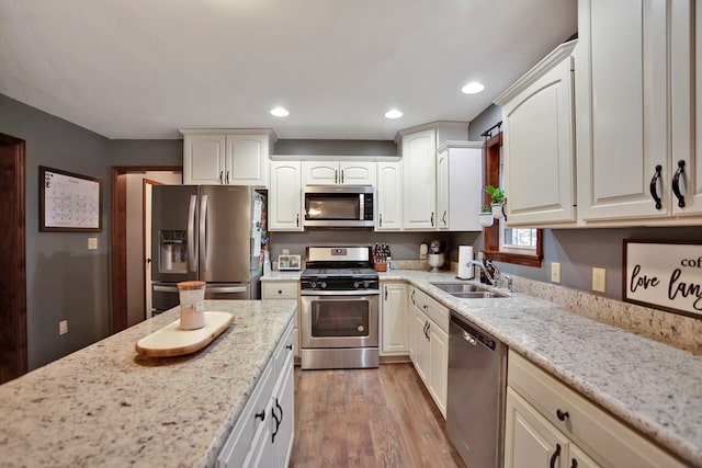 kitchen featuring white cabinets, stainless steel appliances, light stone countertops, and sink